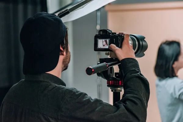 Rear view of videographer with assistant and model working in photo studio — Stock Photo