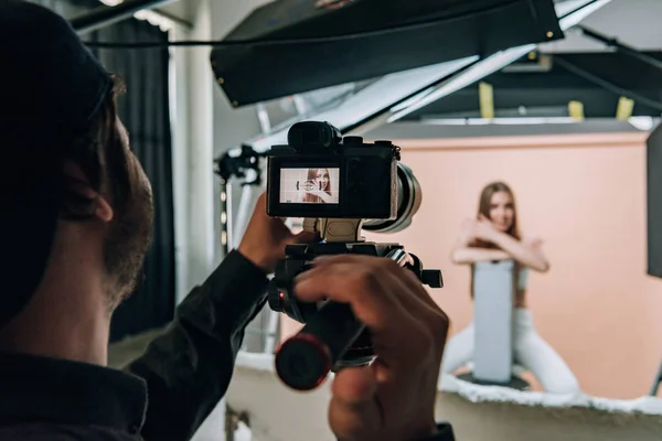 Over shoulder view of videographer filming beautiful model in photo studio — Stock Photo