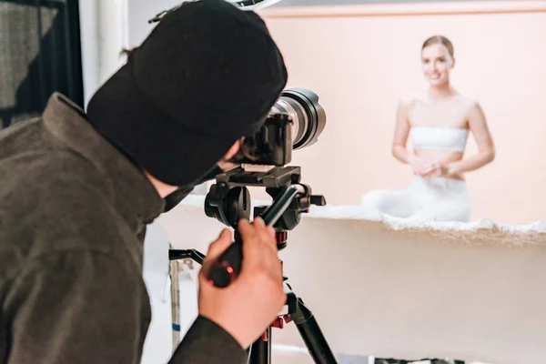 Selektiver Fokus des Kameramanns, der lächelndes Model im Fotostudio fotografiert — Stockfoto