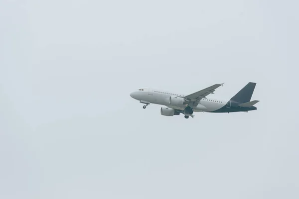 Vue en angle bas de l'atterrissage de l'avion dans un ciel nuageux — Photo de stock