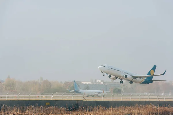 Commercial plane taking off from airport runway with cloudy sky at background — Stock Photo