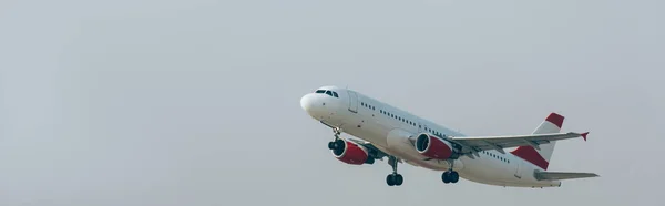 Jet plane taking off in cloudy sky, panoramic shot — Stock Photo