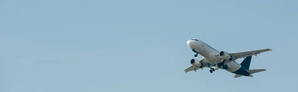 Панорамный снимок самолета, взлетающего в голубом небе с копировальным пространством — стоковое фото