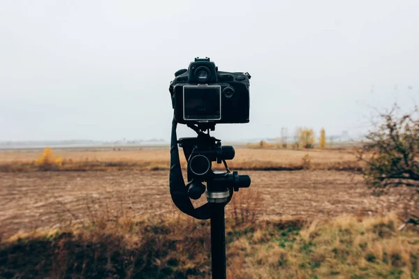 Mise au point sélective de l'appareil photo numérique sur le trépied dans un champ herbeux — Photo de stock