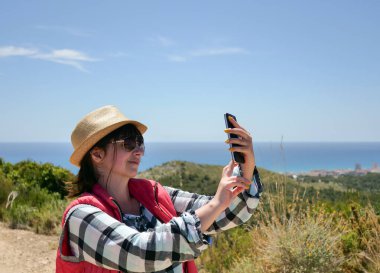 Çekici gülümseyen kız turist dışarıda selfie çekiyor.