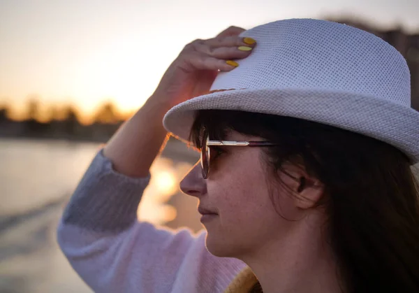 Portrait d'une jeune fille séduisante en chapeau blanc sur la plage le soir au coucher du soleil, gros plan — Photo