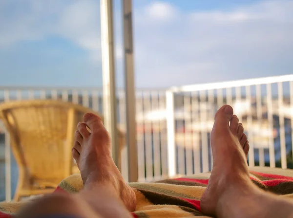 Pieds masculins sur le lit sur fond de balcon ouvert — Photo