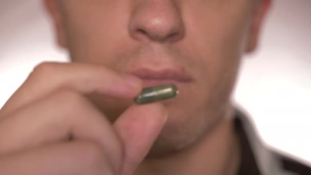緑の錠剤を食べ 水を飲む男のクローズアップ — ストック動画
