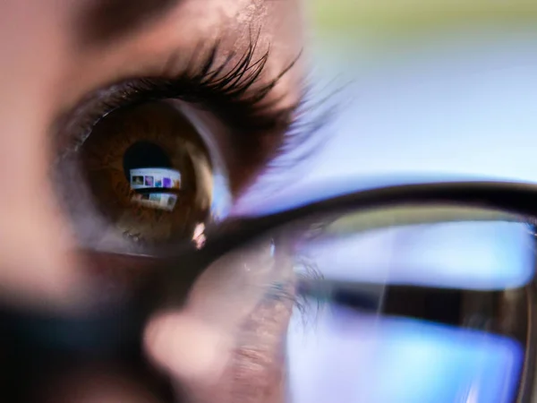 Menina de olhos castanhos em óculos olha para um monitor de laptop, close-up Imagem De Stock