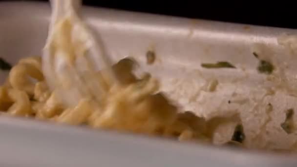 一个饥肠辘辘的男人用塑料叉子从容器里吃面条，这是特写镜头 — 图库视频影像