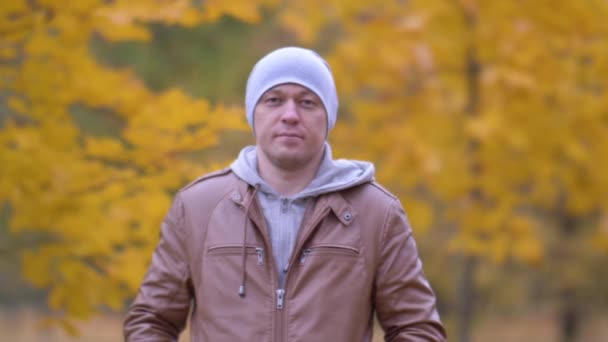Egy fiatalember jól néz ki az őszi parkban. — Stock videók