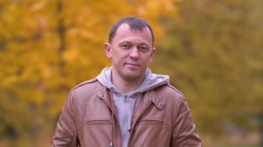 Sonbahar ormanında seksi bir gülümsemesi olan çekici bir genç adamın portresi.