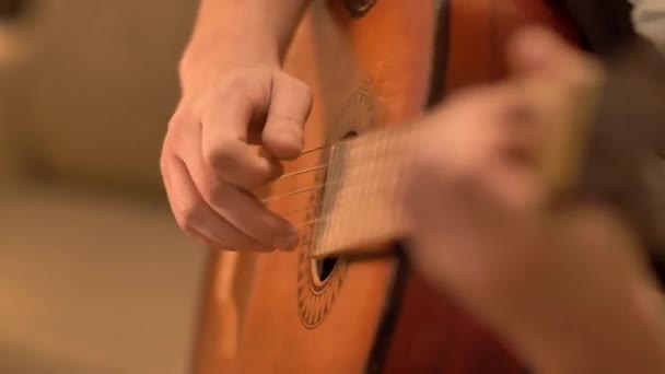 Bir adam eski klasik bir gitarın tellerini seçiyor, ağır çekimde. — Stok video