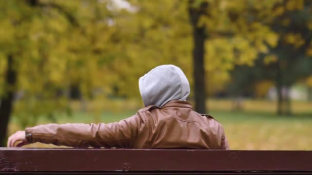 Uomo Sconosciuto Cappuccio Seduto Una Panchina Del Parco Sta Guardando — Video Stock
