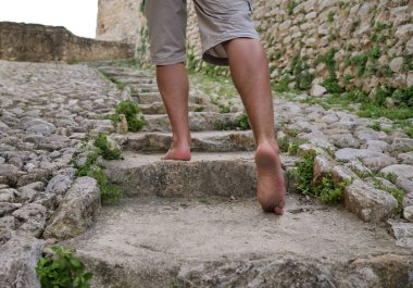 Erkek turist taş basamaklarda yalın ayak yürüyor.