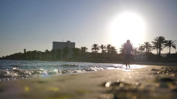 Sylwetka Młodego Mężczyzny Kapeluszu Szortach Spaceruje Plaży Zachodzie Słońca — Wideo stockowe