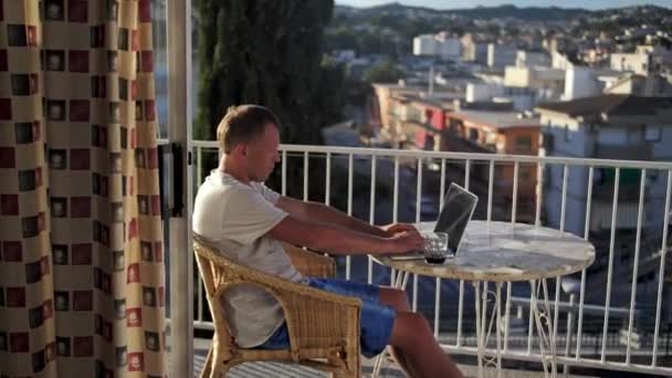 Homme indépendant travaillant sur son ordinateur portable assis sur le balcon — Video