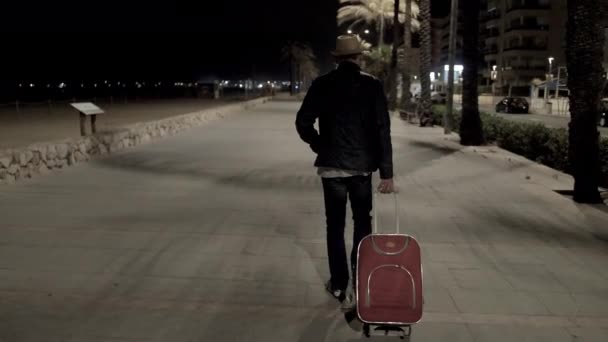 The guy the tourist in a hat and a suitcase goes late at night on the street — 비디오