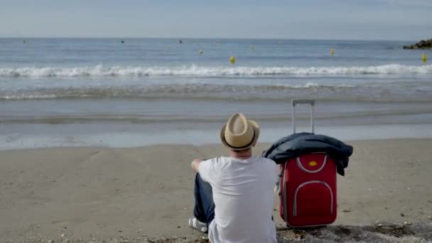 Giovane turista di sesso maschile seduto sulla spiaggia, venuto a riposare — Video Stock