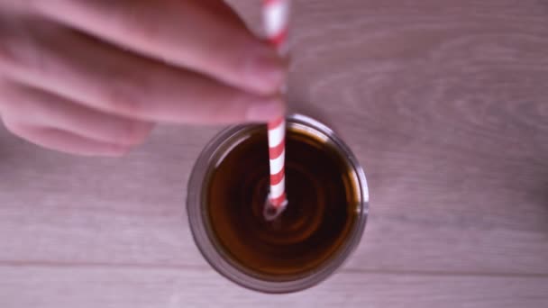 Мужчина пьет из стакана напиток через яркую соломинку, пьет газировку, на светлом фоне — стоковое видео