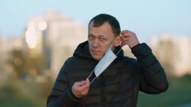 Sokak arka planında genç bir adamın portresi. Yüzüne maske takıyor. Sağlık kavramı