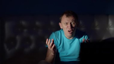 Bir adam gece evde oturur ve televizyon izler, güçlü sürprizler, güçlü duygular hisseder.