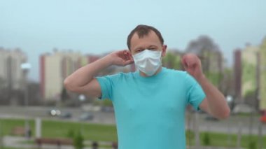 Genç adam sokakta duruyor ve tıbbi bir maske çıkarıyor, sağlık konsepti, salgının sonu.