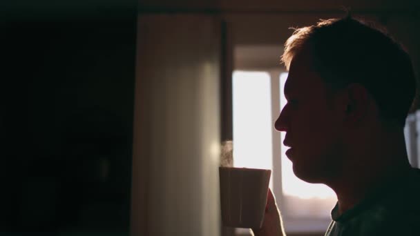 日の出を背景にホットコーヒーのマグカップを持つ男のシルエット — ストック動画