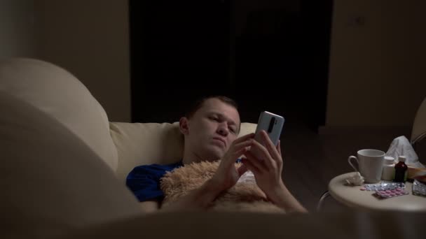 Evening Man Lies Alone Couch Sick Uses His Phone — Stock Video