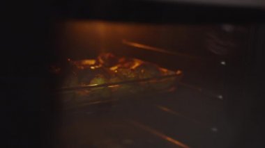 Bir adam fırından pişmiş yemek tabakasını çıkarır.