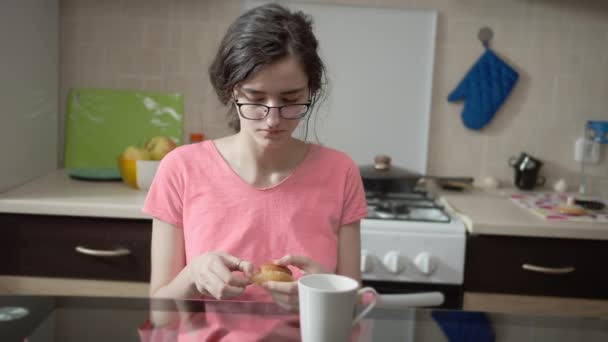 魅力的なブルネットの女の子は台所の背景にマフィンを食べる — ストック動画