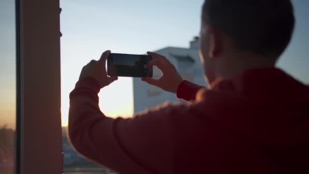 El joven está disparando una puesta de sol en un teléfono celular — Vídeo de stock