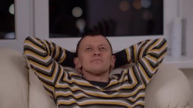 Genç adam evinde kanepede oturmayı hayal ediyor.