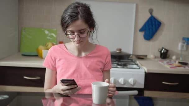 Милая Брюнетка Сидящая Кухне Используя Свой Мобильный Телефон Завтраком — стоковое видео