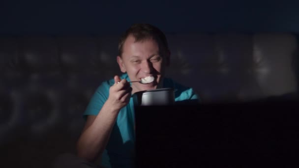Άνθρωπος Κάθεται Στην Τηλεόραση Βράδυ Γελάει Και Τρώει Παγωτό — Αρχείο Βίντεο