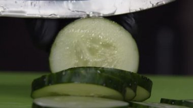 Aşçı taze salatalık dilimliyor, makro shot.