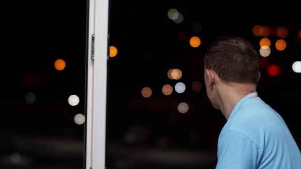 Adam açık pencereden gece şehrine bakıyor.. — Stok video