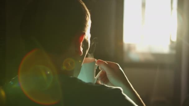 Silhouette eines Mannes mit einem Becher heißen Kaffees vor dem Hintergrund des Sonnenaufgangs — Stockvideo