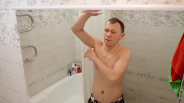 Genç adam sabah banyoda dururken deodorant kullanıyor.