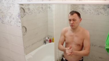 Bir adam ellerini sabunla yıkar ve havluyla siler.