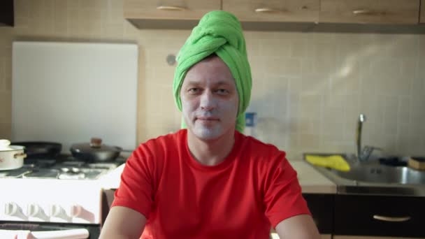 Hübscher Mann mit Kosmetikmaske im Gesicht und Handtuch auf dem Kopf — Stockvideo