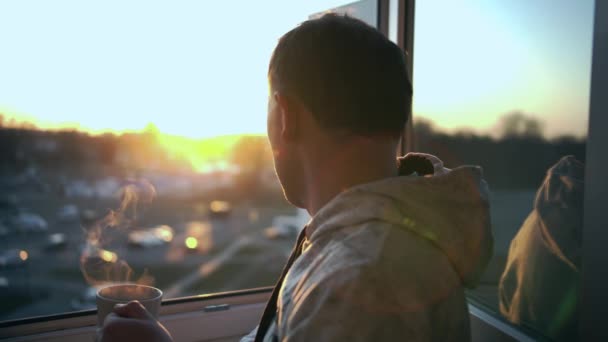 Homme Tient Dans Une Fenêtre Ouverte Regardant Coucher Soleil Buvant — Video