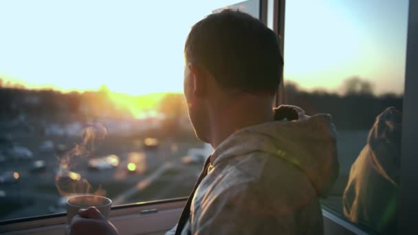 Man Står Ett Öppet Fönster Och Tittar Solnedgången Och Dricker — Stockvideo