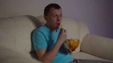 Akşamları TV 'de oturan bir adam ilginç ve heyecan verici bir program izliyor.