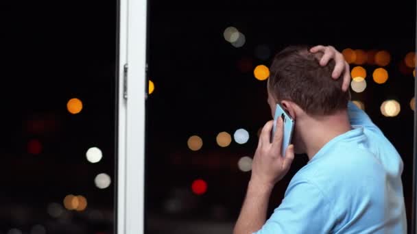 Joven Hablando Por Teléfono Parado Ventana Abierta Por Noche Vista — Vídeos de Stock