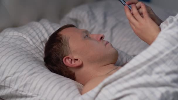 Een man gebruikt een mobiele telefoon voordat hij naar bed gaat.. — Stockvideo