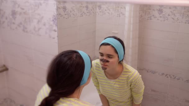 Yüzünde Siyah Kozmetik Maske Olan Genç Güzel Bir Kız Aynada — Stok video