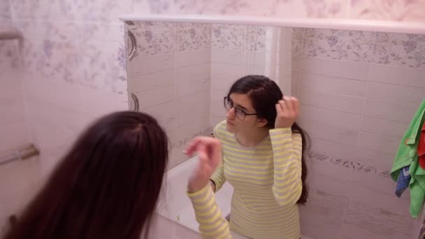 Молодая Красивая Девушка Надевает Очки Смотрит Свое Отражение Зеркале — стоковое видео