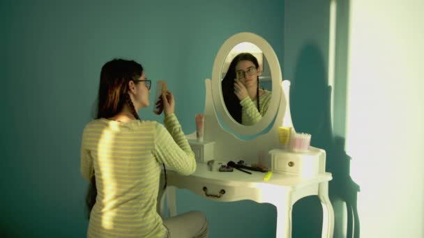 Милая Юная Брюнетка Очках Длинными Густыми Волосами Расчесывающаяся Перед Зеркалом — стоковое видео