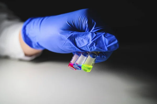 Scientist investigating three colourful solution in different LC